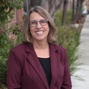 Kate Bristol Ph.D. Focus Strategies Team Headshot Smiling Wearing Purple Glasses And Burgundy Suit Jacket And Black Shirt